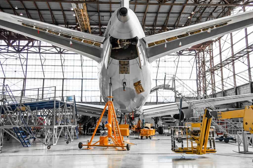 The back of an aeroplane, surrounded by ladders and machinery in a hangar.