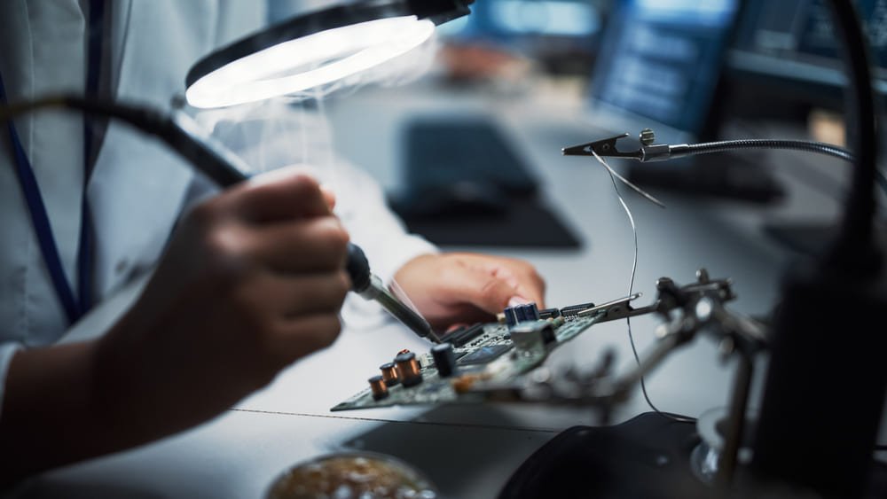 An engineer does computer motherboard soldering.