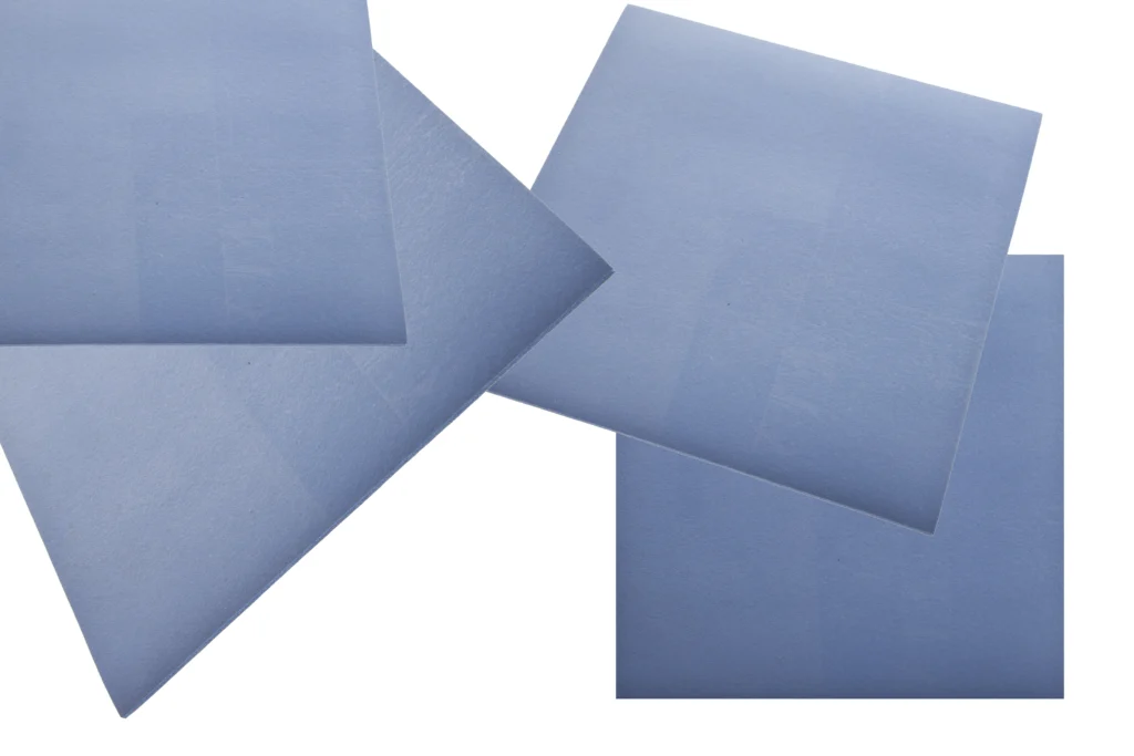 Multiple square pieces of fluorosilicone rubber sheeting scattered across a white background.
