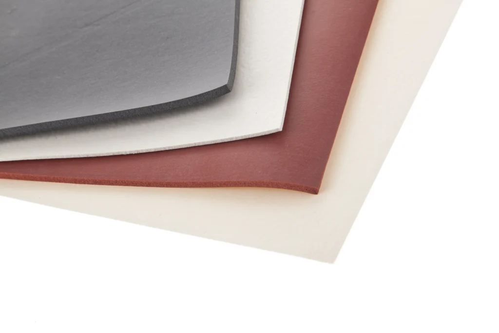 The corner of a pile of different coloured general purpose silicone sponge sheets.